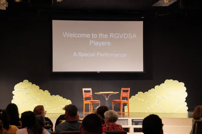 a group of people sitting in front of a screen